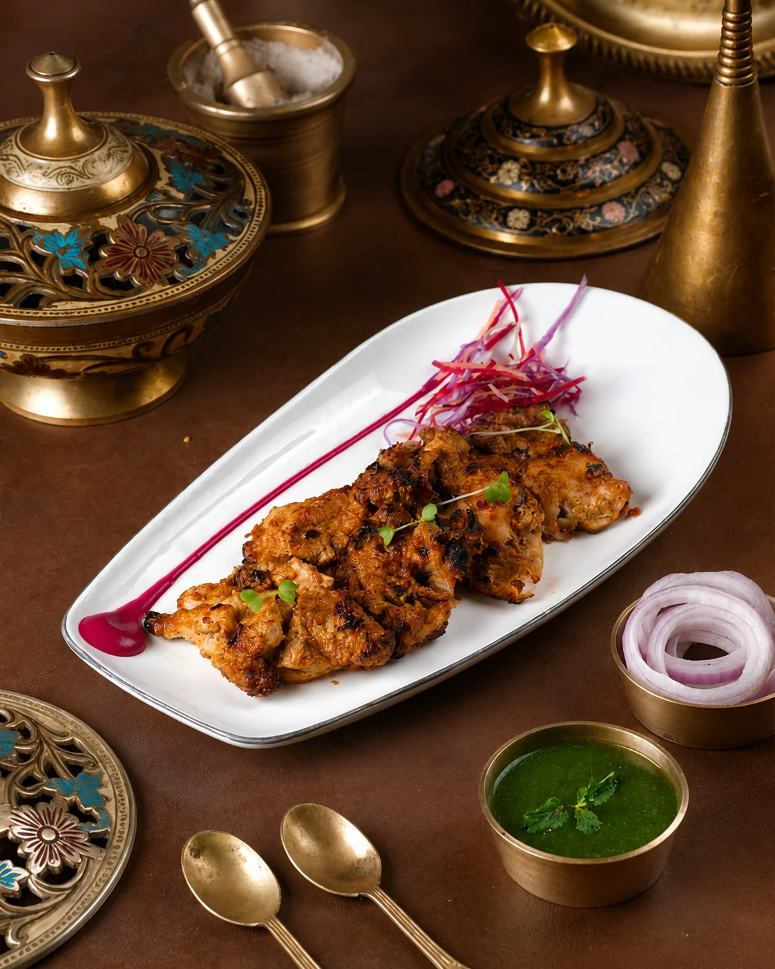 Grilled Chettinad-style chicken served on a platter with mint chutney and onions